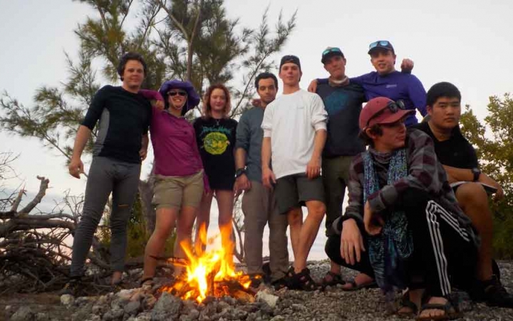 a group of outward bound students pose for a photo beside a campfire 
